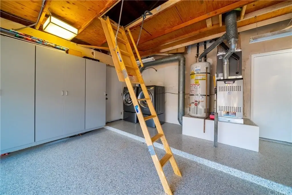 Garage interior with wooden ladder, storage cabinets, and appliances