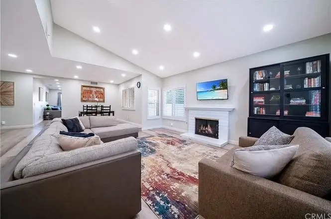 Living room with seating area, fireplace, TV, area rug, and large windows