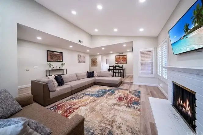 Living room with large sectional sofa, area rug, fireplace, TV, and hardwood floors