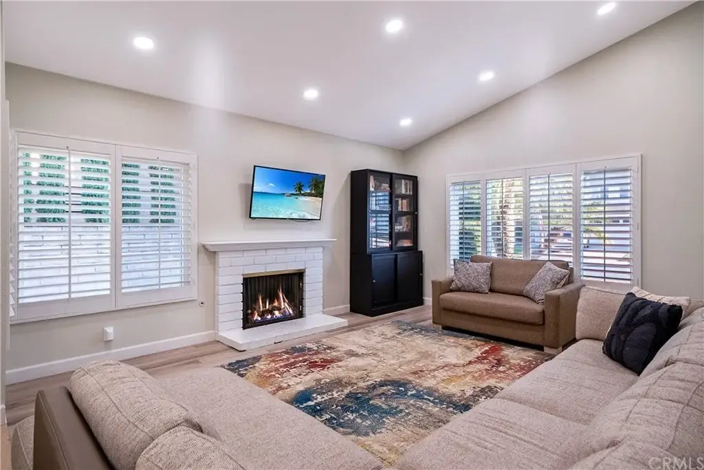 Living room with beige sectional sofa, patterned rug, fireplace, TV, and black cabinet
