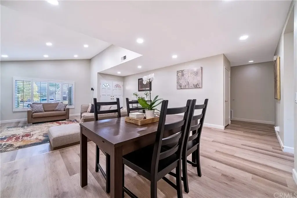 Living space with dining table and black chairs, beige couch, and hardwood floors