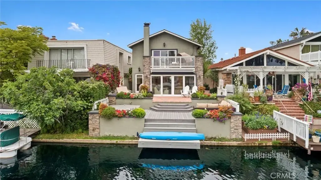 Waterfront house California real estate with large patio, garden, greenery, and dock.