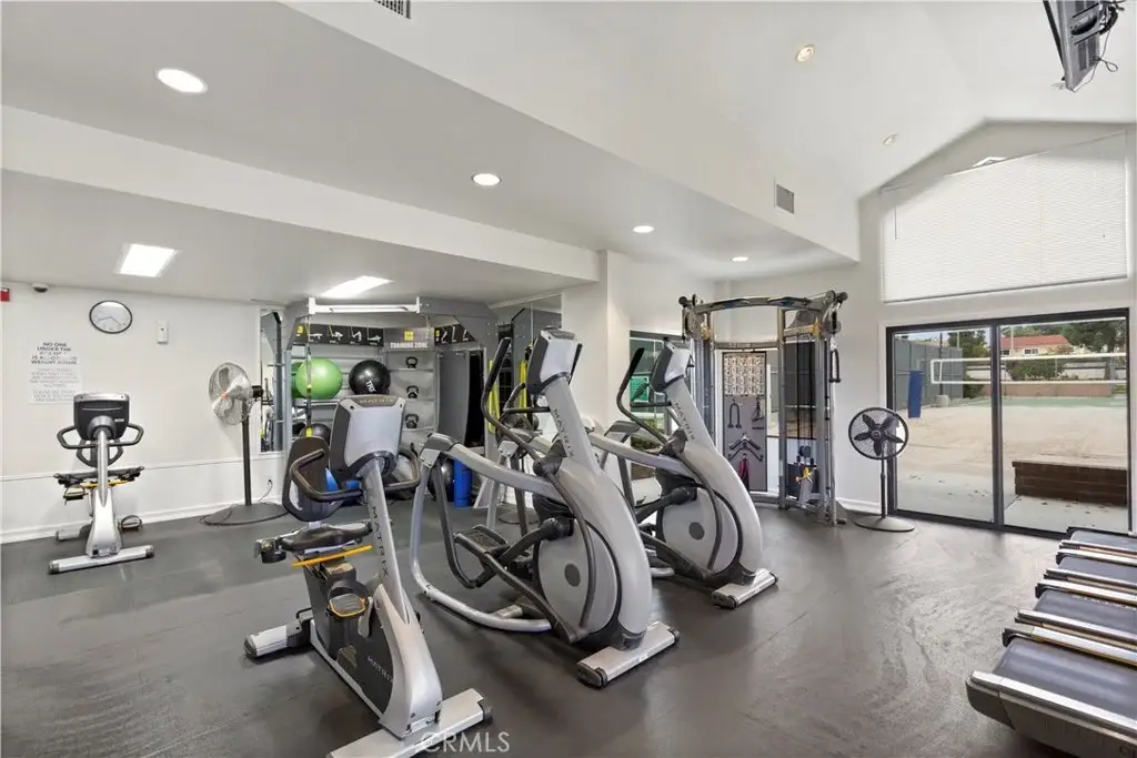Gym with elliptical machines, bikes, weights, and big windows.