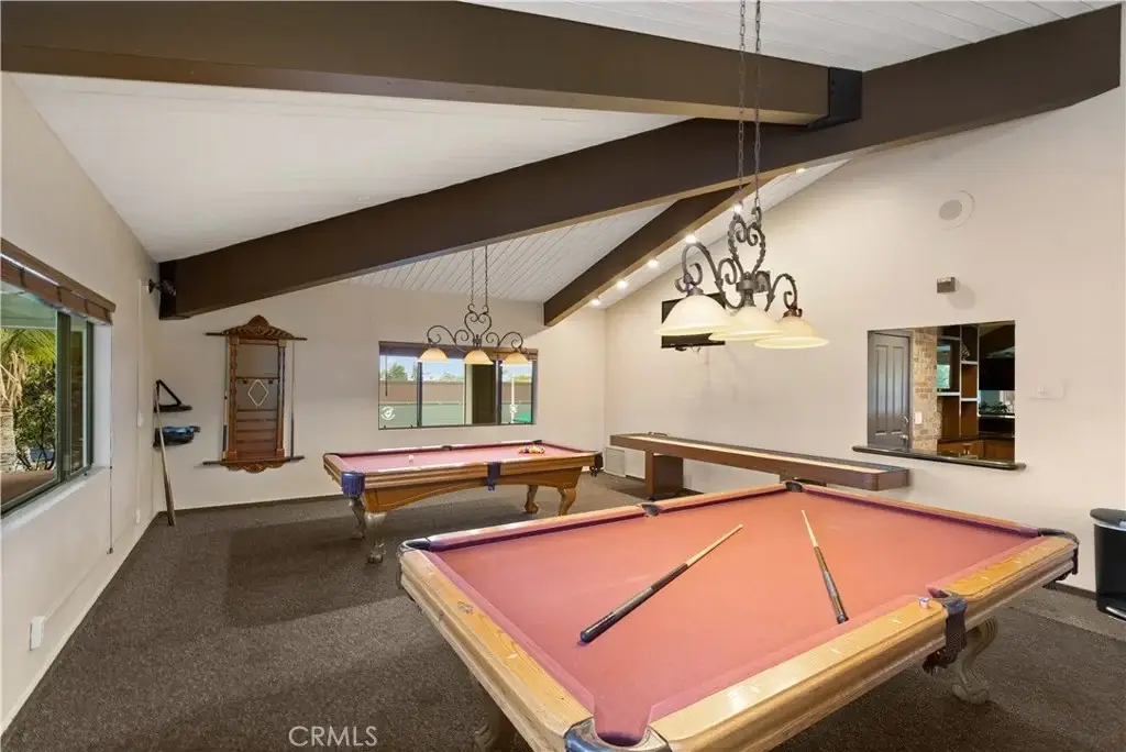 Game room with two pool tables, big window, ceiling beams, and lights.