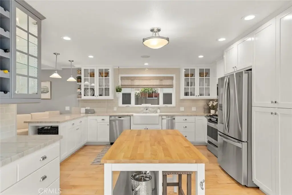 Kitchen with white cabinets, wood island, and stainless appliances.