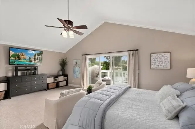 bedroom with large bed, ceiling fan, wall TV, dresser, and sliding glass doors to patio.