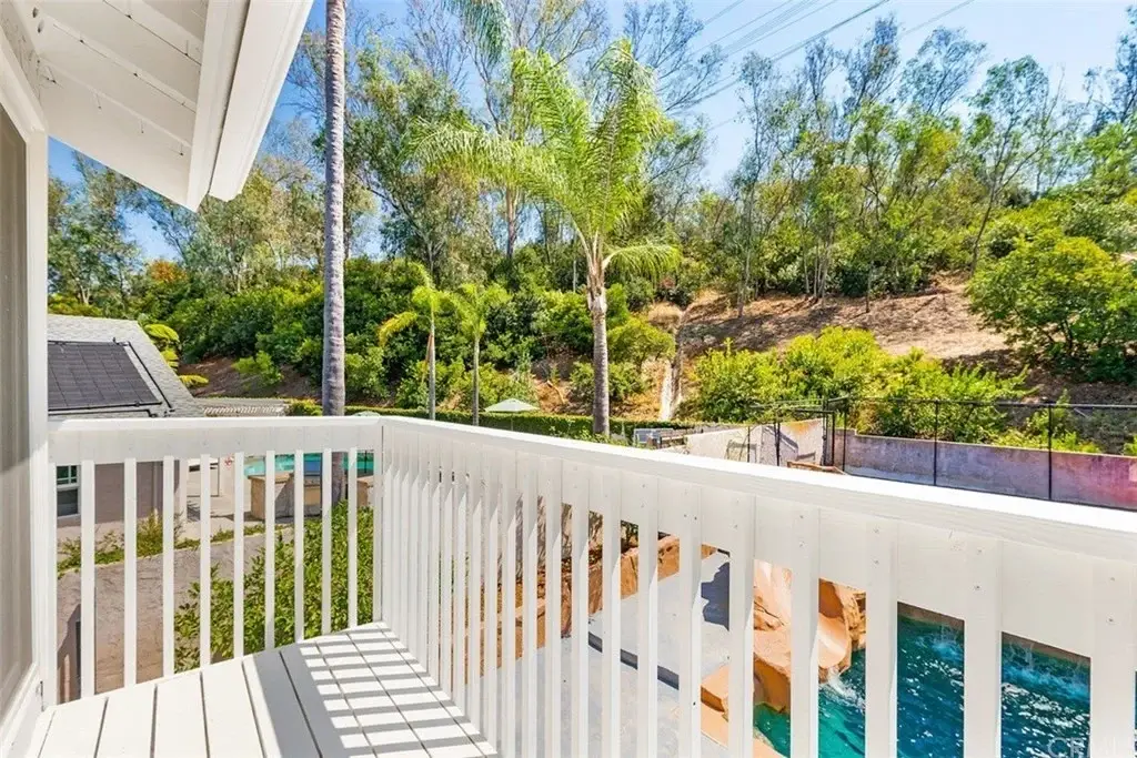 Balcony view with green trees, plants, and swimming pool