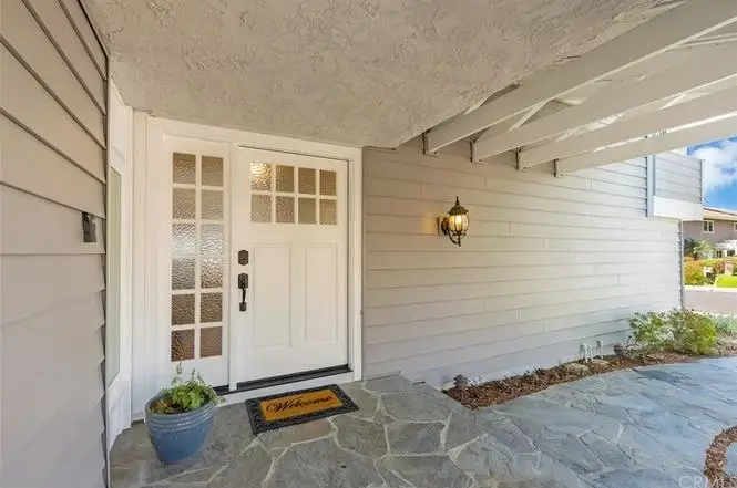Front porch with welcome mat, stone floor, and glass-panel door