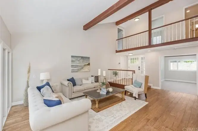 Living room with light sofa, coffee table, wooden floor, and staircase