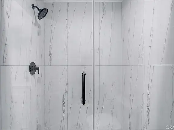 Bathroom with bathtub, patterned tile backsplash, white vanity, and black fixtures