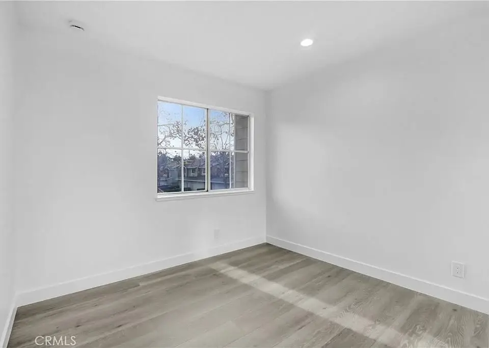 Empty room with light wood floor, white walls, and single window