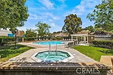 Outdoor area with swimming pool, hot tub, trees, and lounge chairs