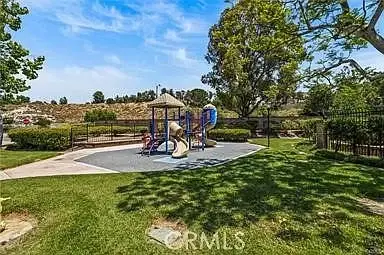Playground with slides, climbing structures, greenery, and fence
