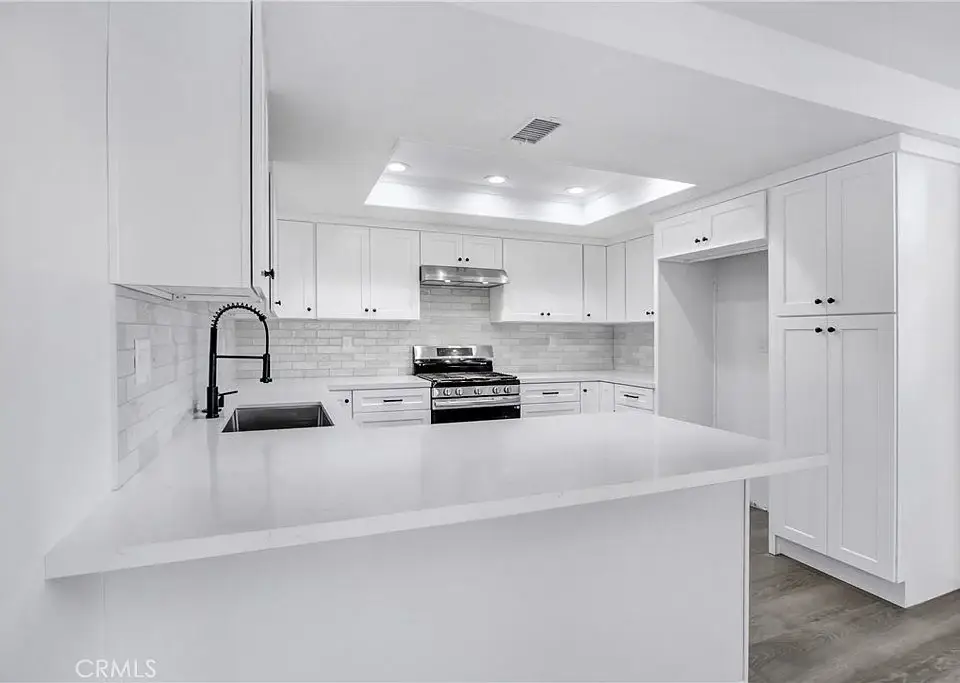 Kitchen with white cabinets, stainless steel stove, and large countertop