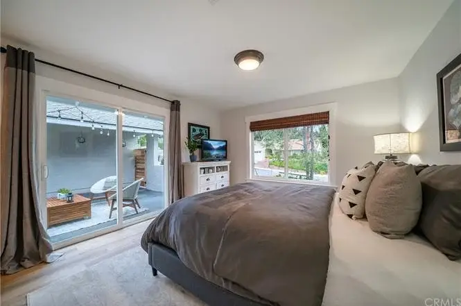 Bedroom with large bed, bedside lamp, dresser, and sliding glass doors to outdoor space