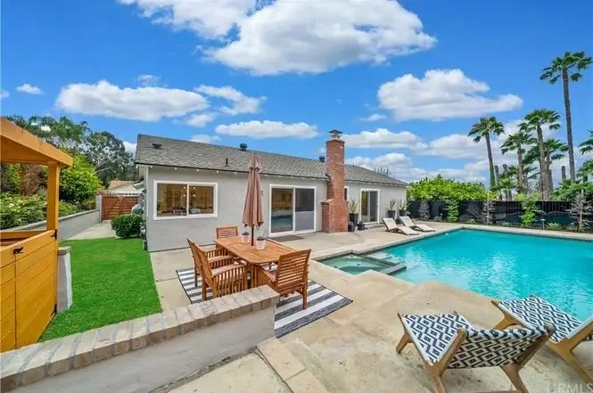 Backyard with swimming pool and patio furniture, large house California real estate in background
