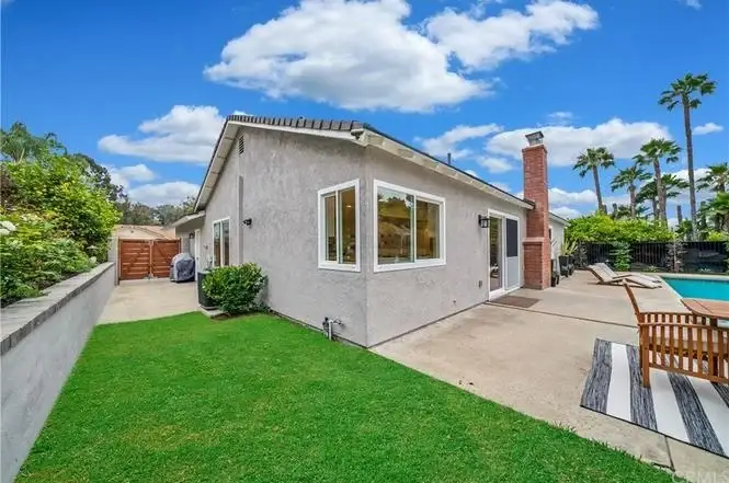 Luxurious house California real estate with pool, green lawn, and palm trees