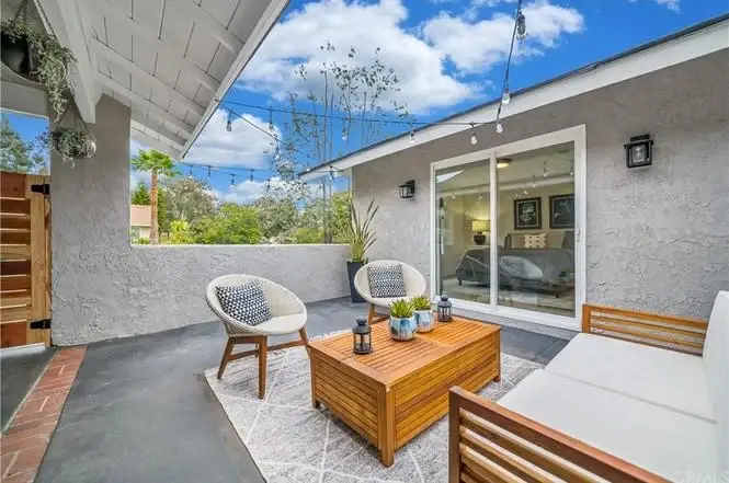 Outdoor seating area with two chairs, wooden table, and house California real estate walls