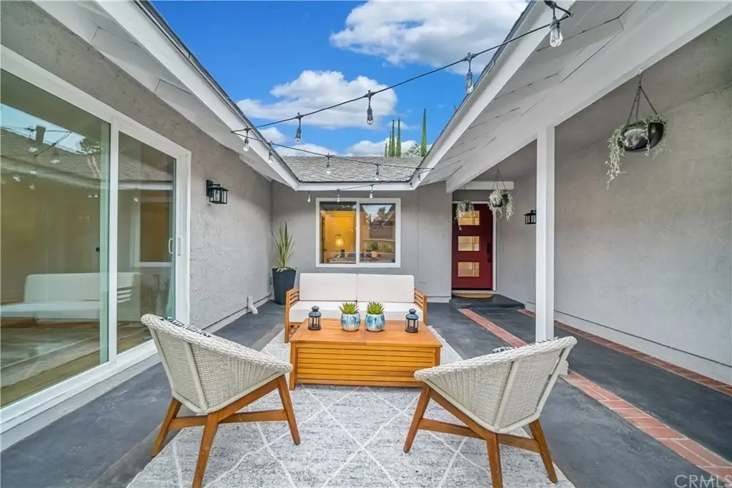 Outdoor seating area with two chairs, wooden table, and plants