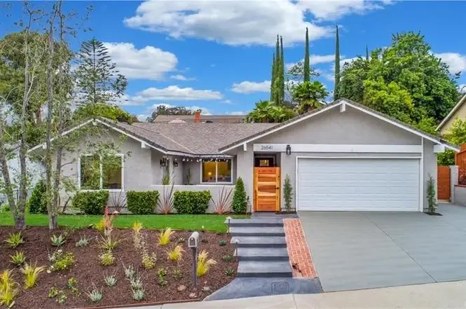 Luxurious house California real estate with landscaped front yard, plants, trees, driveway, and garage