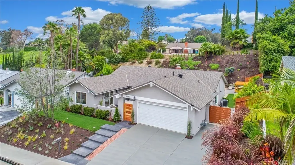 Aerial view of large house California real estate with landscaped yard, driveway, and trees