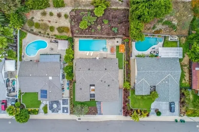 Aerial view of houses California real estate with swimming pools and landscaped gardens along a residential street