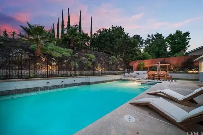 Pool area with lounge chairs and landscaped greenery and trees