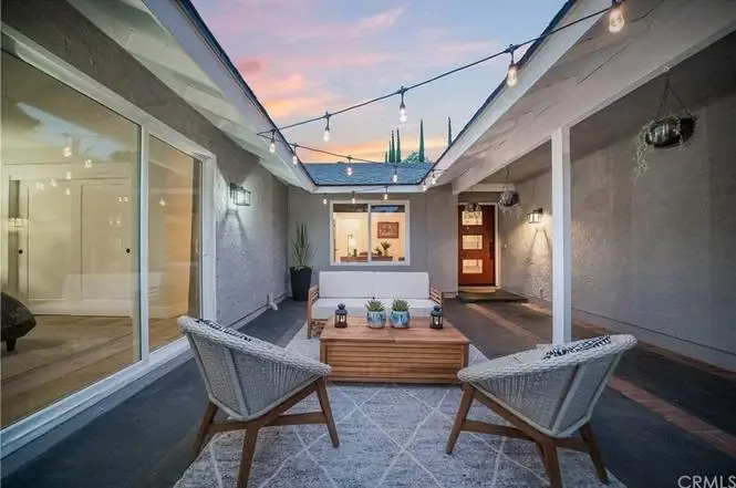 Outdoor patio with two chairs, wooden coffee table, and string lights