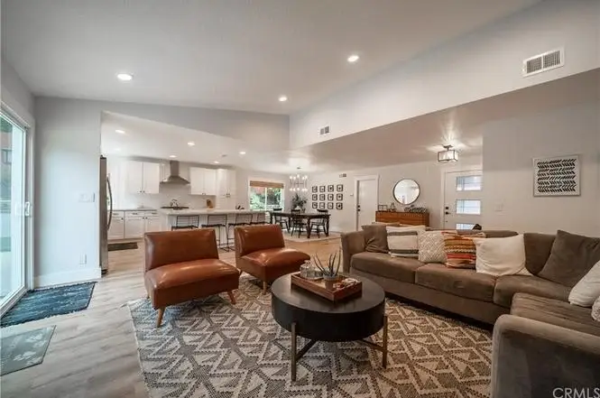 Living room with sectional couch, two leather chairs, coffee table, sliding doors, and patterned rug