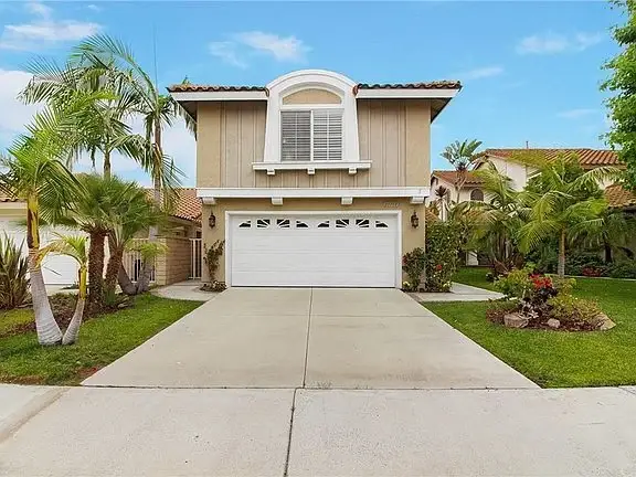 A luxury home in California real estate with two floors and palm trees.