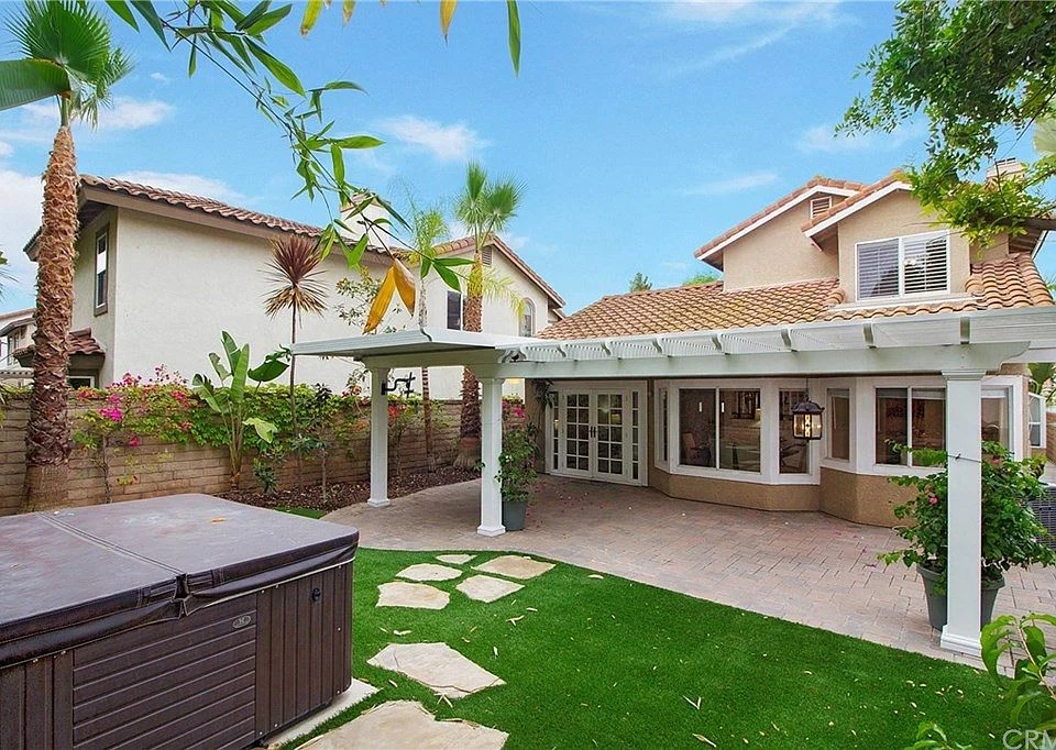 Backyard of house California real estate with patio, hot tub, stone path, and plants.