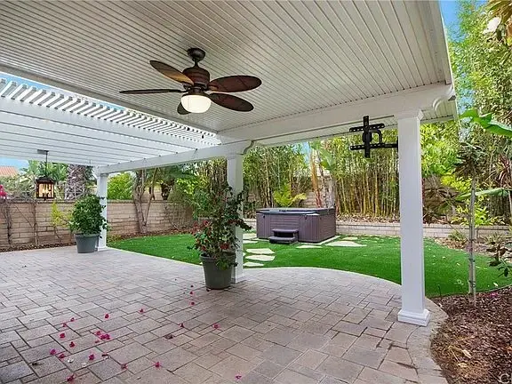 Patio of house California real estate with ceiling fan, hot tub, and plants.
