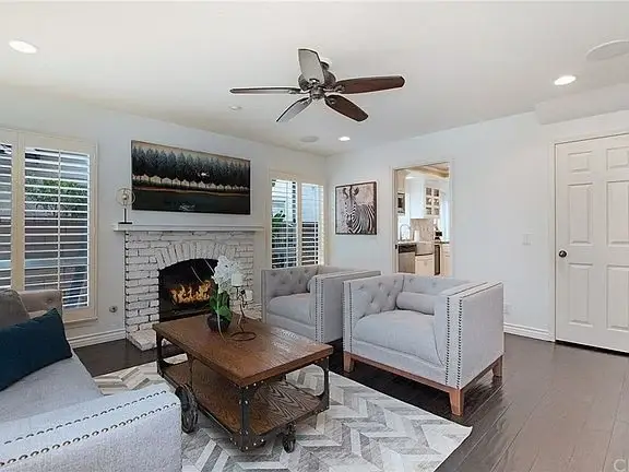 Living room with fireplace, two armchairs, gray sofa, coffee table, and windows