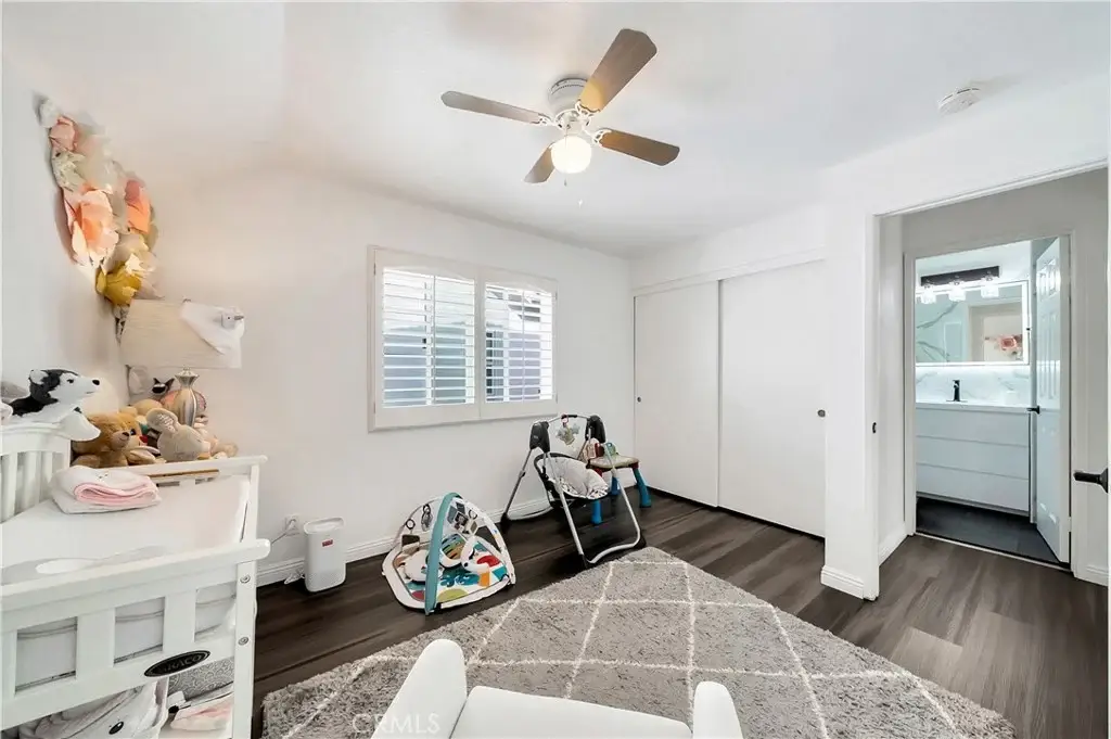 Nursery with crib, plush toys, changing table, ceiling fan, and door to bathroom.