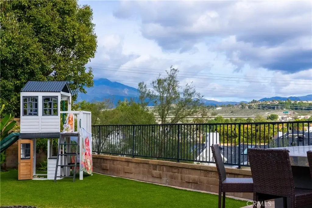 Backyard of house California real estate with playhouse, green grass, mountains,