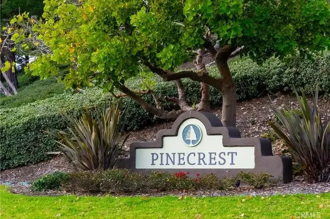 Sign that says PINECREST with green plants and landscaping.