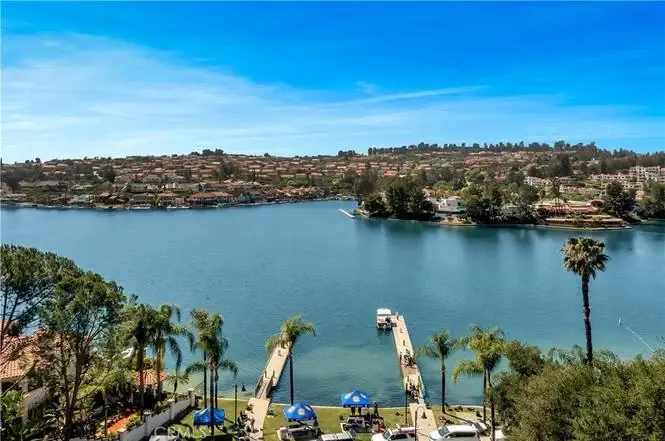 View of lake with houses California real estate, hills, and palm trees.