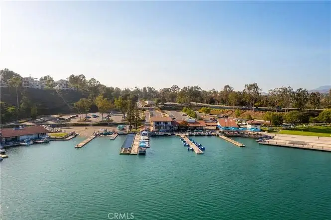 Aerial view of marina with docks, boats on blue lake, and green trees around.