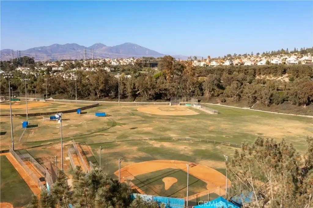 Aerial view of baseball field complex with green fields, dirt infields, and mountains in the background.