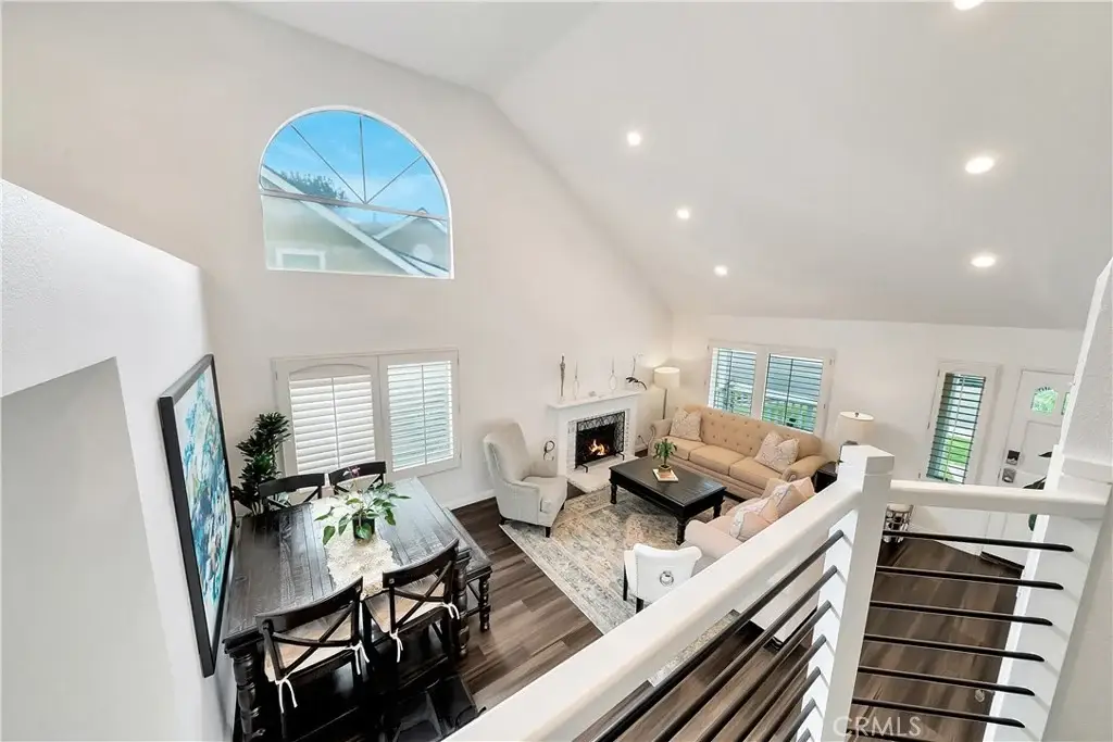 Living space with beige sofa, coffee table, rug, dining table, big windows, and fireplace.