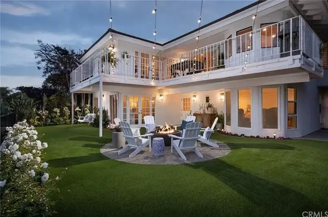 Two story house California real estate backyard with fire pit, adirondack chairs, plants, flowers, and string lights.