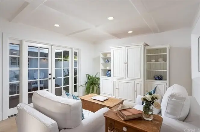Living room with white furniture, wood coffee table, built in shelves, decor, and glass doors.