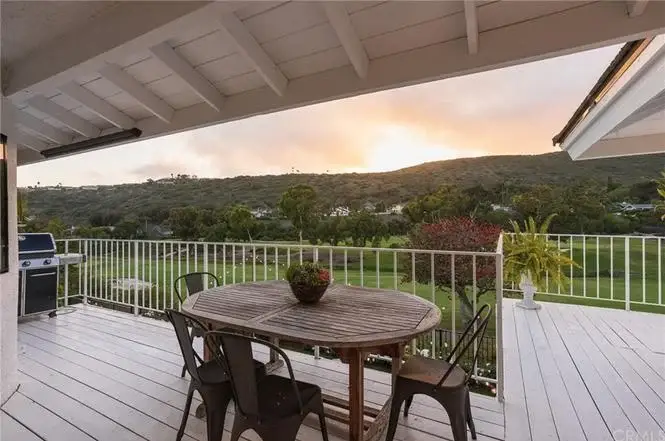 Balcony of house California real estate with wooden table, metal chairs, plant, grill
