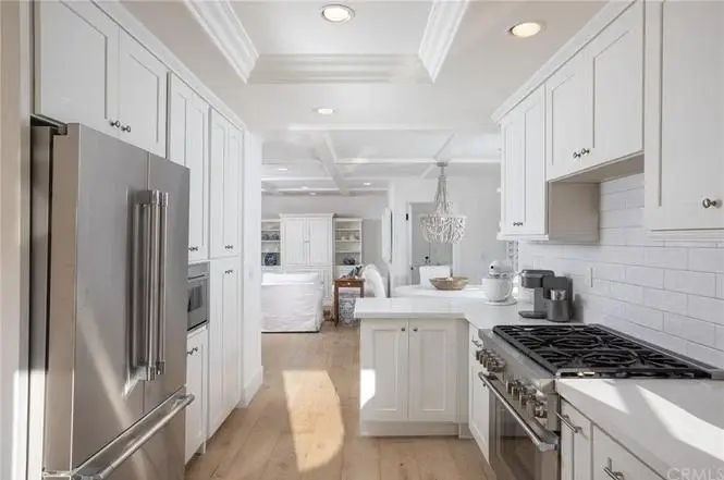 Kitchen with white cabinets, stainless steel appliances, gas stove, and windows.