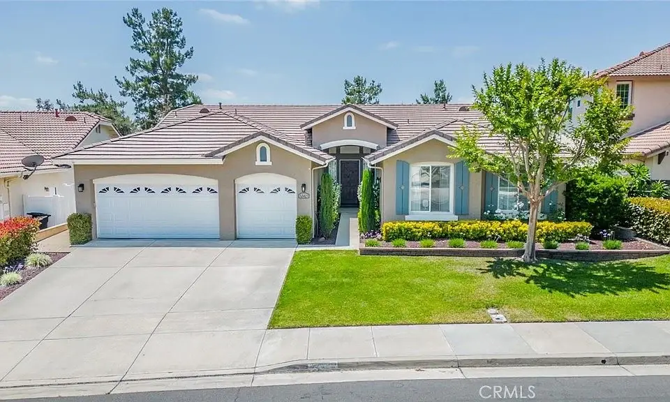 California real estate house with two-car garage, lawn, trees, and shrubs in front yard