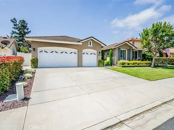 California real estate house with beige exterior, two-car garage, and landscaped yard