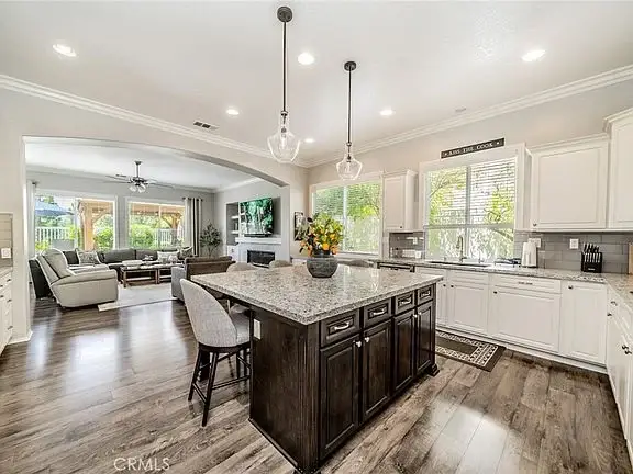 Kitchen with island, white cabinets, and living area with gray sofas