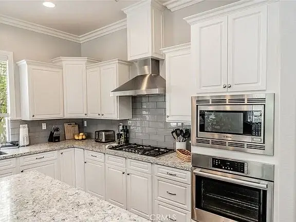 Kitchen with white cabinets, granite countertops, stainless steel appliances, and modern design