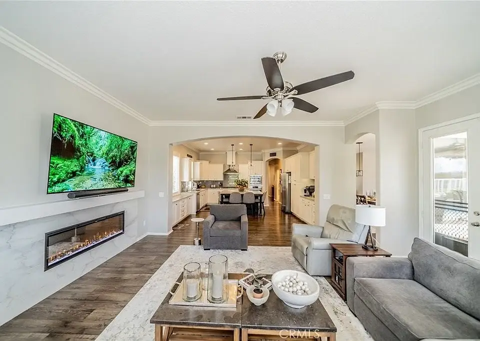 Living room with flat-screen TV, electric fireplace, gray sofa, armchairs, and coffee table