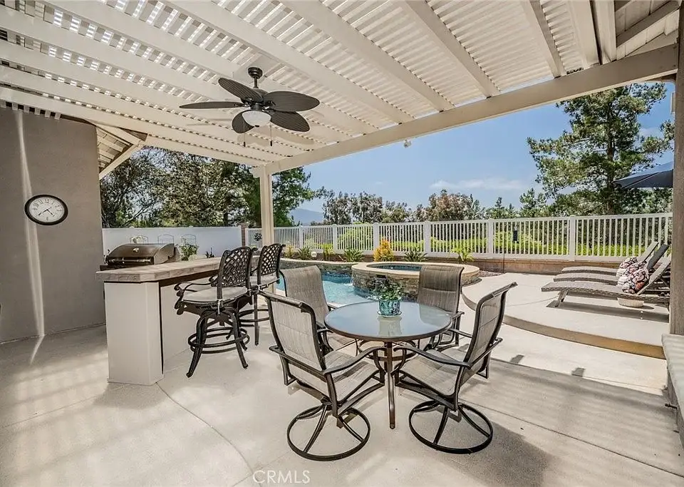 Patio with dining set, barbecue grill, pergola, swimming pool, and greenery
